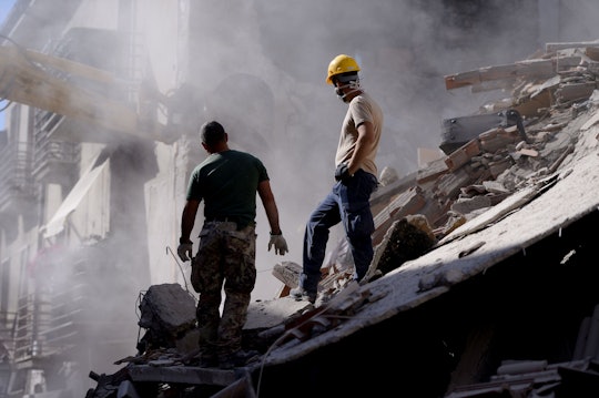 Two men standing next to the Italy earthquake demolished buildings