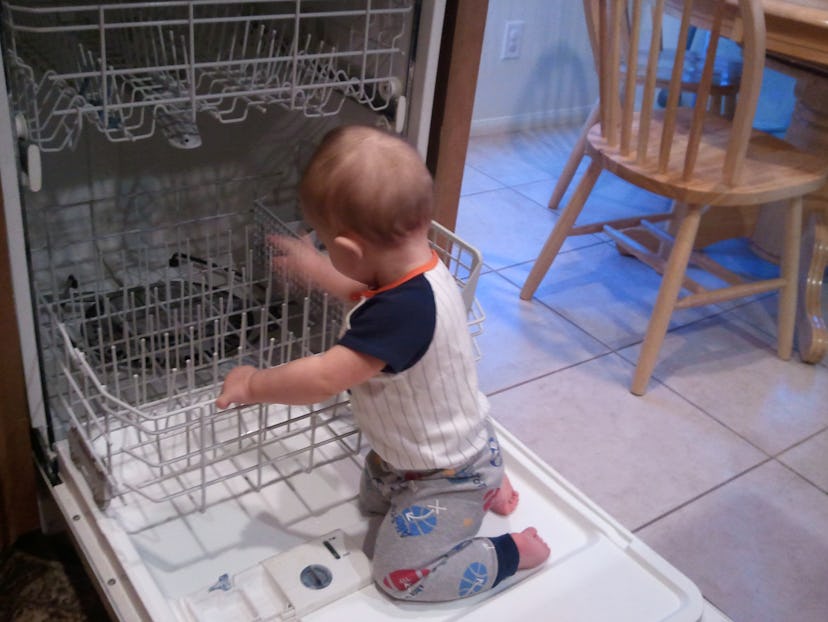A toddler playing with a dish washer 