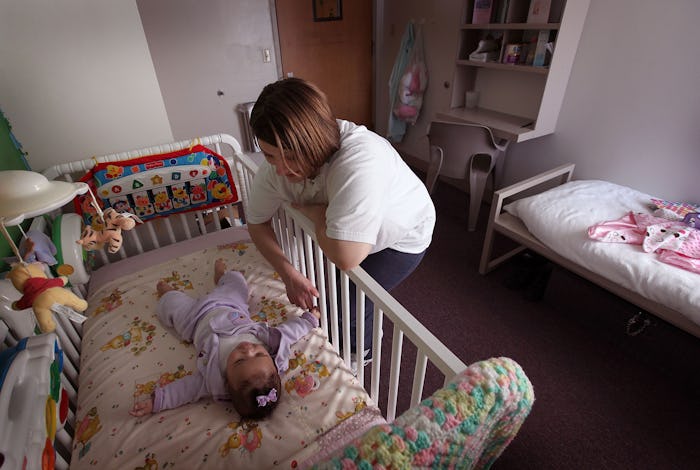 Mom standing next to her babies crib while doing sleep training