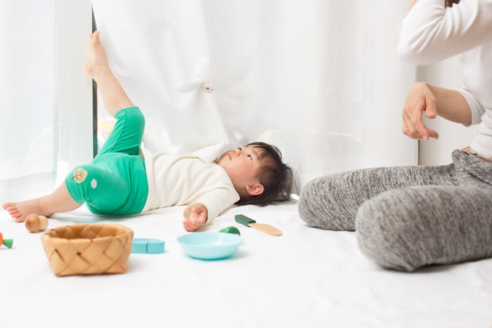 A toddler boy lying on floor next to his mother