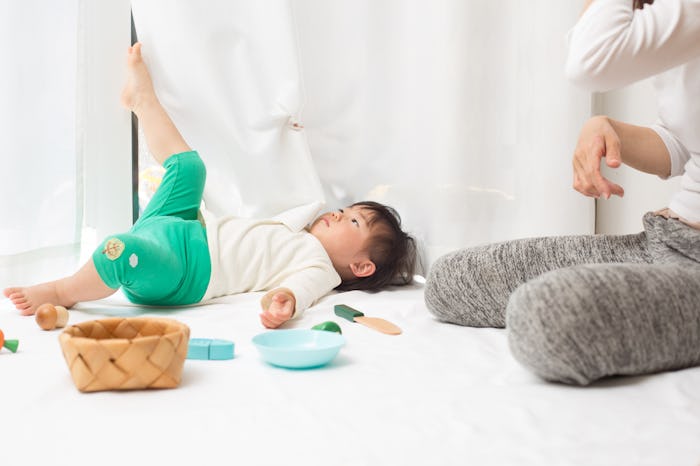 A toddler boy lying on floor next to his mother