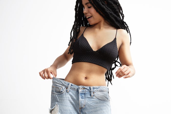 A body positive mom posing in wide trousers after losing weight