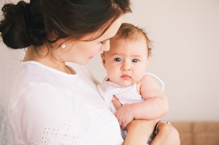 A mother smiling while holding her baby