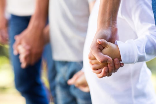 A father and his two sons holding hands.
