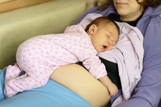 A woman lying on a couch co-sleeping with her newborn baby.