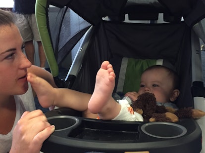 Single mom kissing her son's feet while he is in the baby carriage