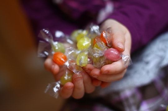 A toddler having hands full of free candy