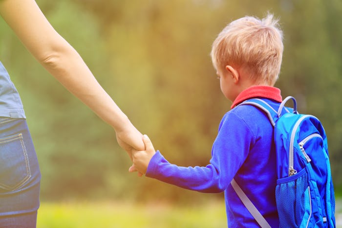 Mom holding her sons hand as she takes him to school