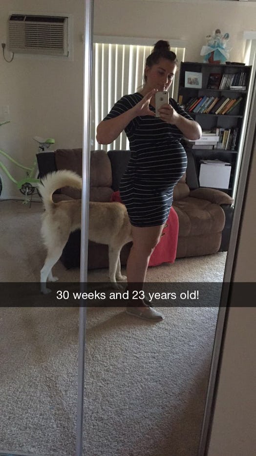 Haley DePass taking a mirror selfie during her late pregnancy with her dog next to her