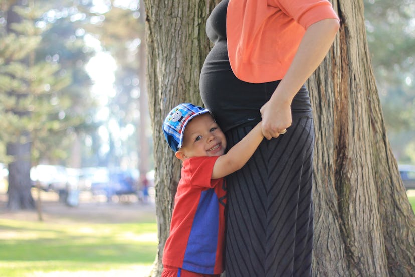 Samantha Taylors' son hugging her in the park, while in the focus is the boy and her pregnant belly