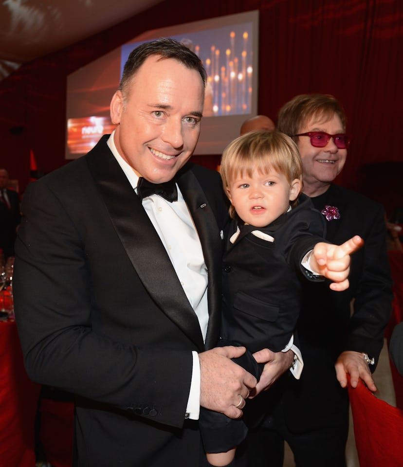  Elton John and his husband David Furnish holding their surrogate-born child