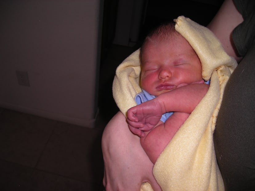 Christi Cazin holding her newborn baby wrapped in a yellow blanket