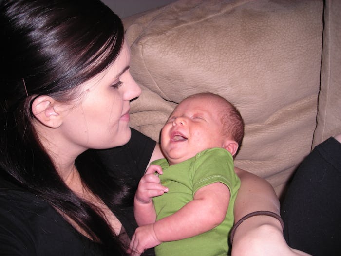 Christi Cazin holding her newborn baby while sitting on a couch