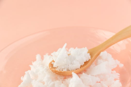 A wooden spoon on a plate with semi-solid coconut oil