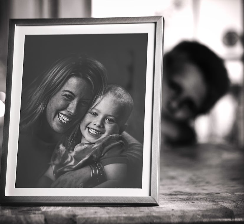 A framed photograph of the mom and the girl who has Leukemia on a wooden surface