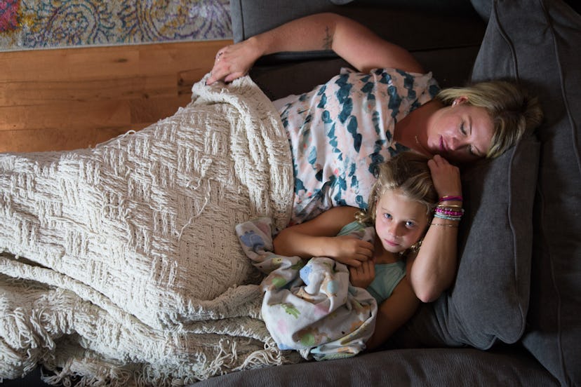 A mother and her daughter who has had Leukemia lying curled up on a couch