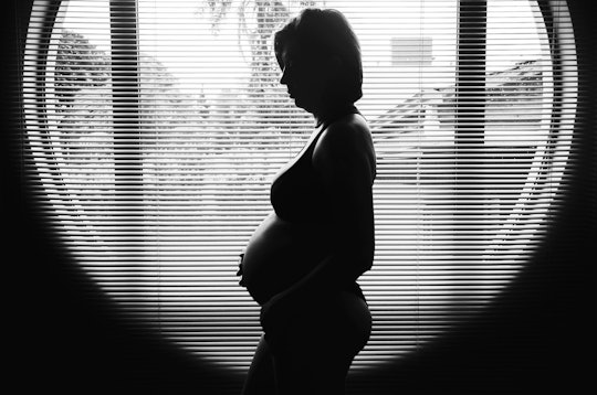 can you get pregnant without fallopian tubes? Black and white photo of pregnant woman standing in fr...