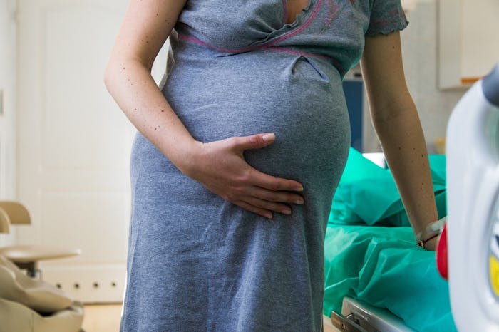 A closeup of a woman's belly and her holding onto it as she goes into labor
