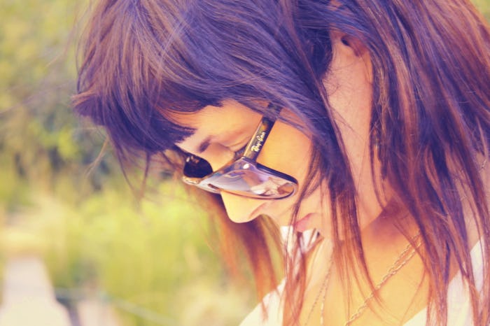 A brunette woman who is a functional alcoholic looking down through her shades