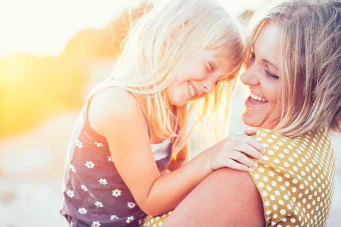 A mother laughing with her daughter while carrying her
