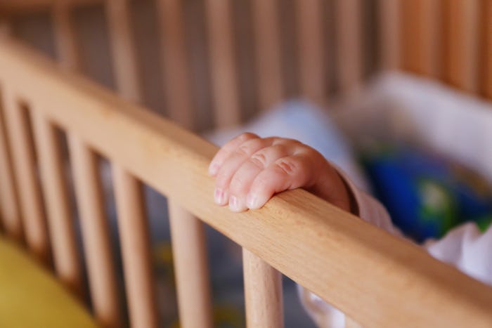 A baby's hand on the side of the crib 