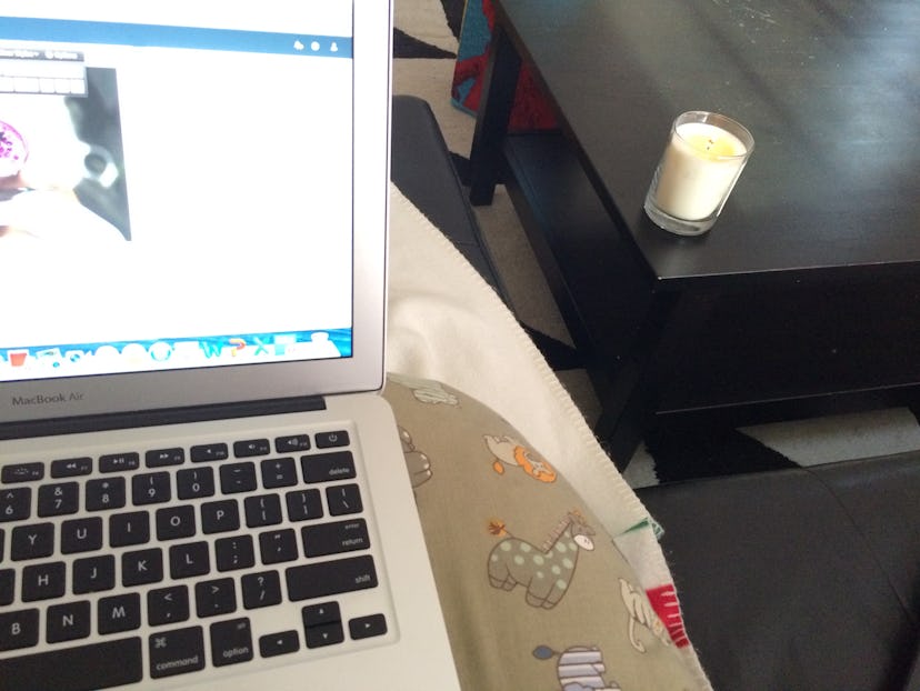 Girl taking the picture where the laptop is visible on her lap, as well as the burning candle on the...