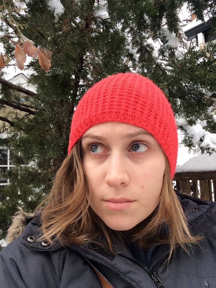 A woman taking a selfie while wearing a red winter cap