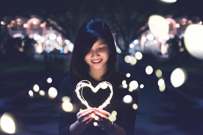 A woman holding a glowing heart 
