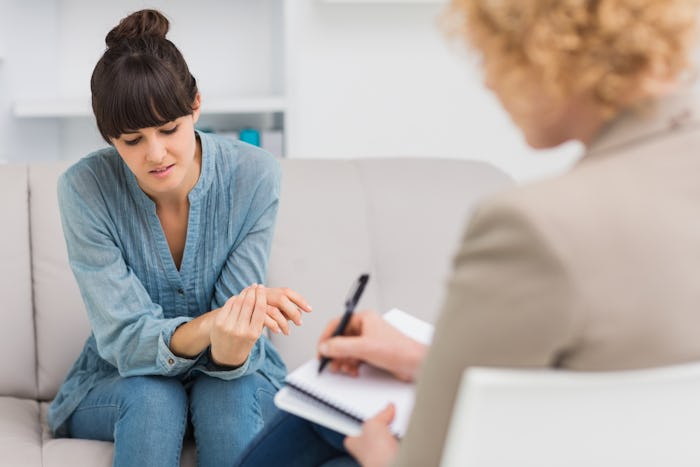 A woman sitting in therapy as the therapist takes notes