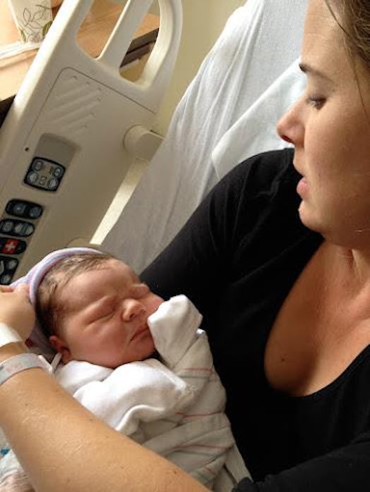 A mother holding her newborn baby while lying in a bed