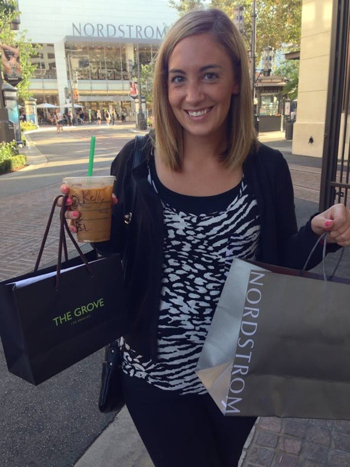 Kelly Clay smiling while holding shopping bags in front of the store
