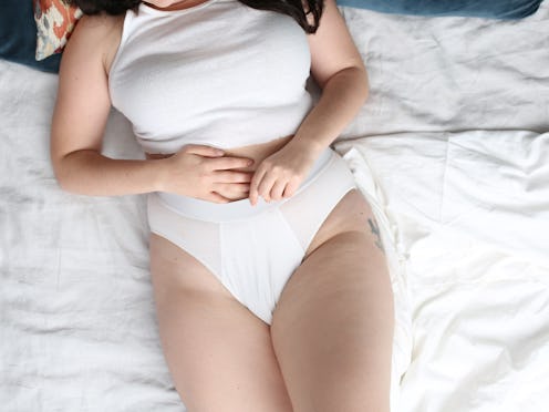 A woman lying in her bed in white underwear whose trauma affects her digestive health