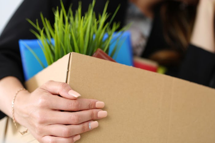 A woman carrying a box full of accessories after quitting a job