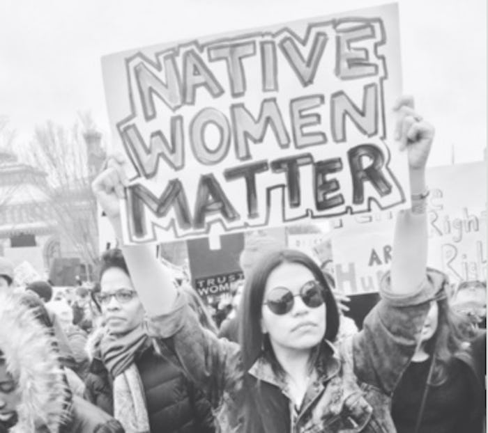 A group of indigenous women marching in a protest with a poster with the text 'NATIVE WOMEN MATTER'