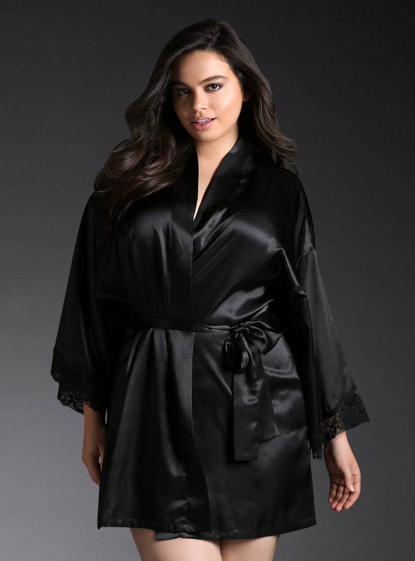 A plus size model posing in a black satin robe