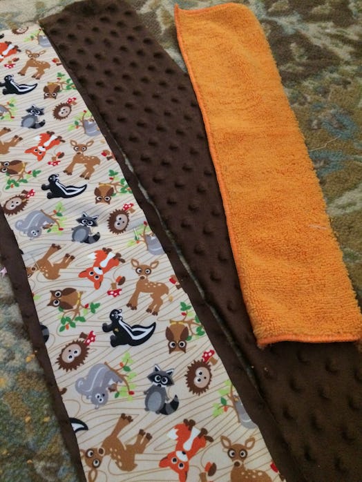 Three pieces of fabric layed out, one with animal design and the other two orange and brown.