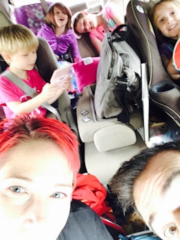 A woman taking a selfie while sitting in a van full of kids 