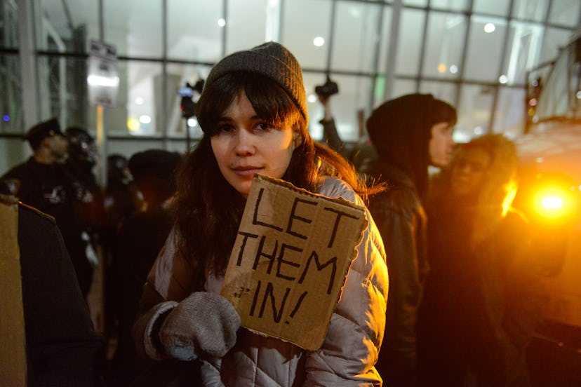 A girl holding a sign "let them in!"