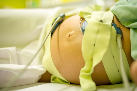 A pregnant woman in a hospital bed with tubes and attachments around her stomach before her epidural