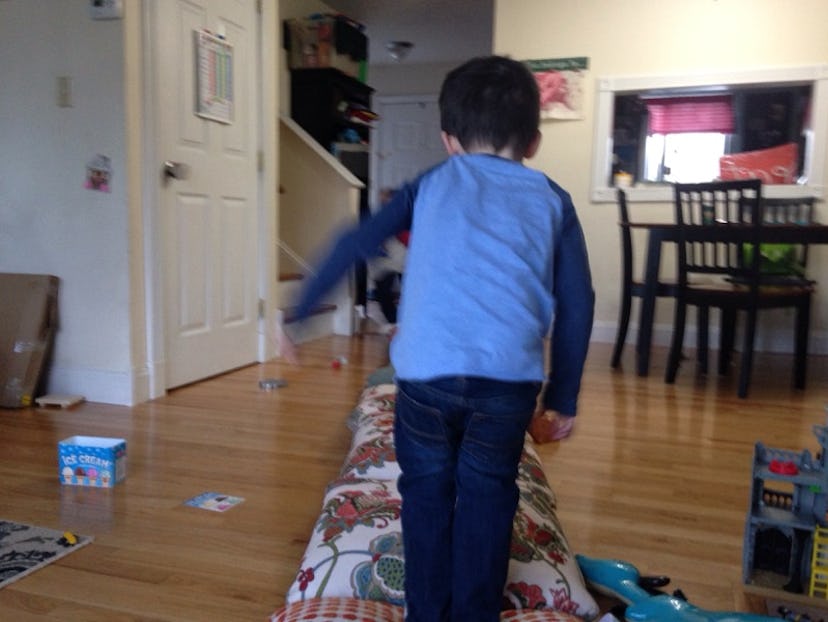 A boy in a blue shirt playing in the living room