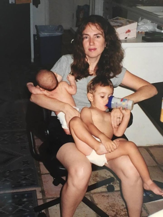 A mother sitting and holding her two kids on her lap