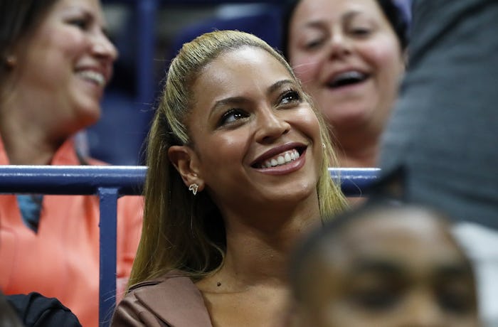 A closeup of Beyoncé with her hair half-up, looking up and smiling