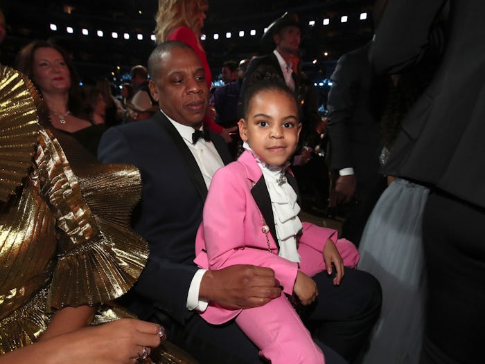Blue Ivy wearing a pink suit sitting in Jay Zs lap at the grammys.