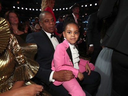 Blue Ivy wearing a pink suit sitting in Jay Zs lap at the grammys