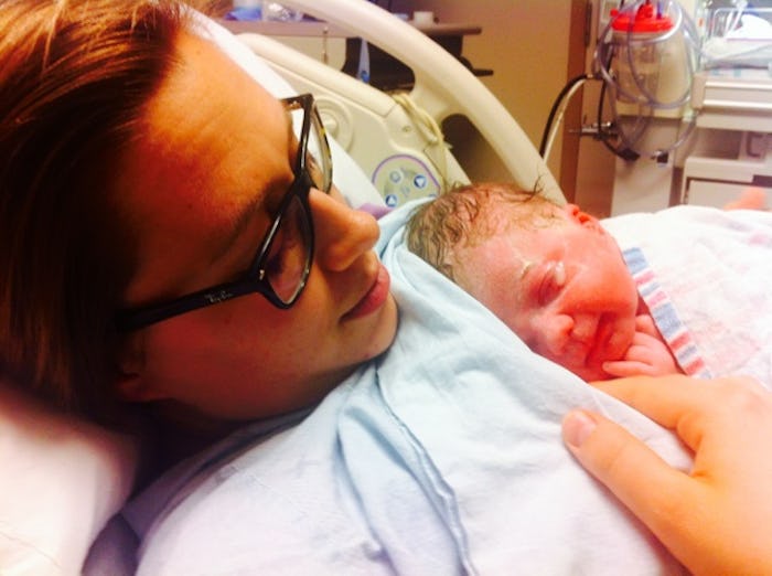 A woman who's just given birth lying in a hospital bed with her newborn baby sleeping on her chest