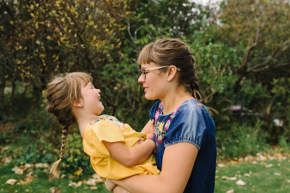 A boss mom holding and playing with her daughter in a park