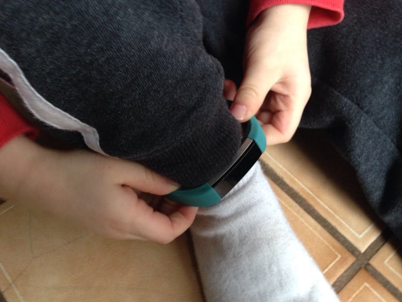 A 4-year-old putting a Fitbit on his leg