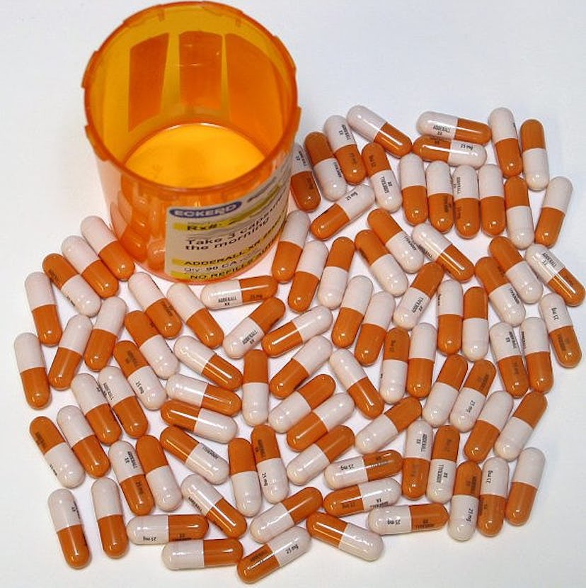 Empty orange pills container and many ADHD tablets spilled on the table