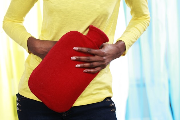 A woman holding her hot water bottle on the belly