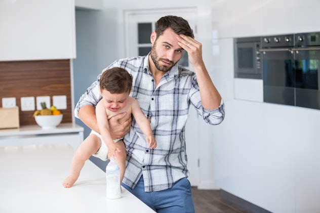 A father holding his head and carrying his crying kid 